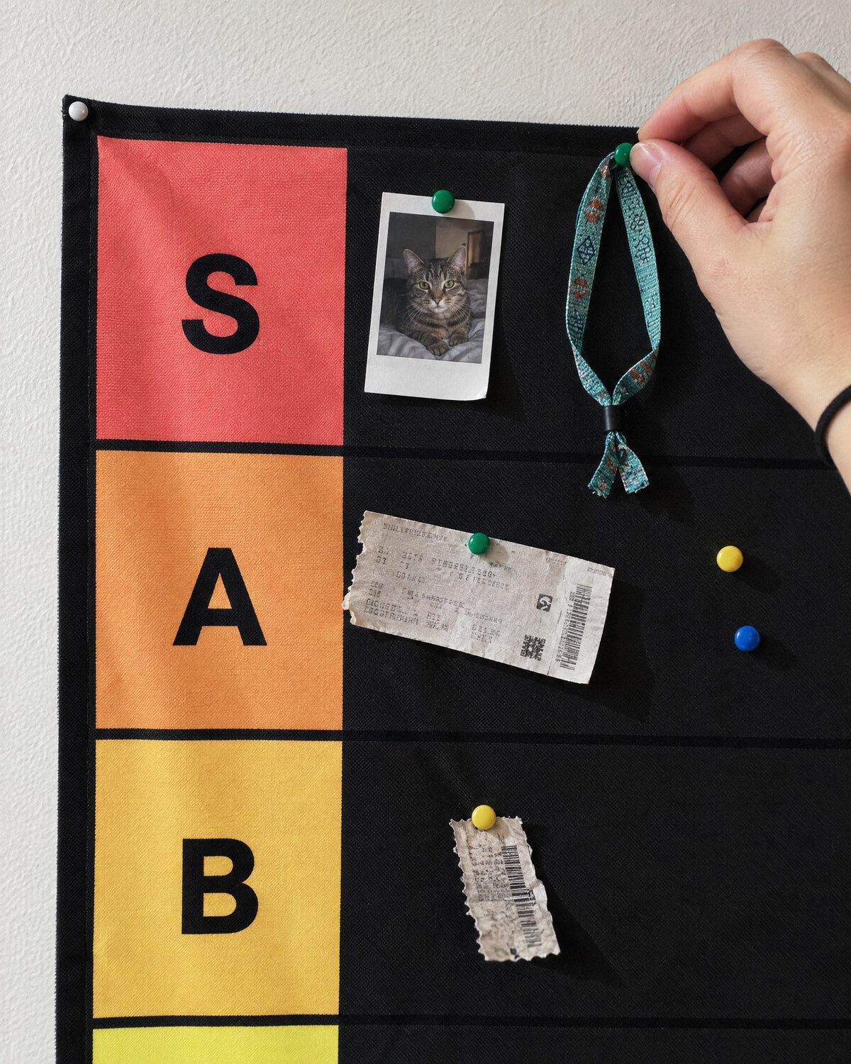 A hand pushing a pin through a festival wristband into the S tier row