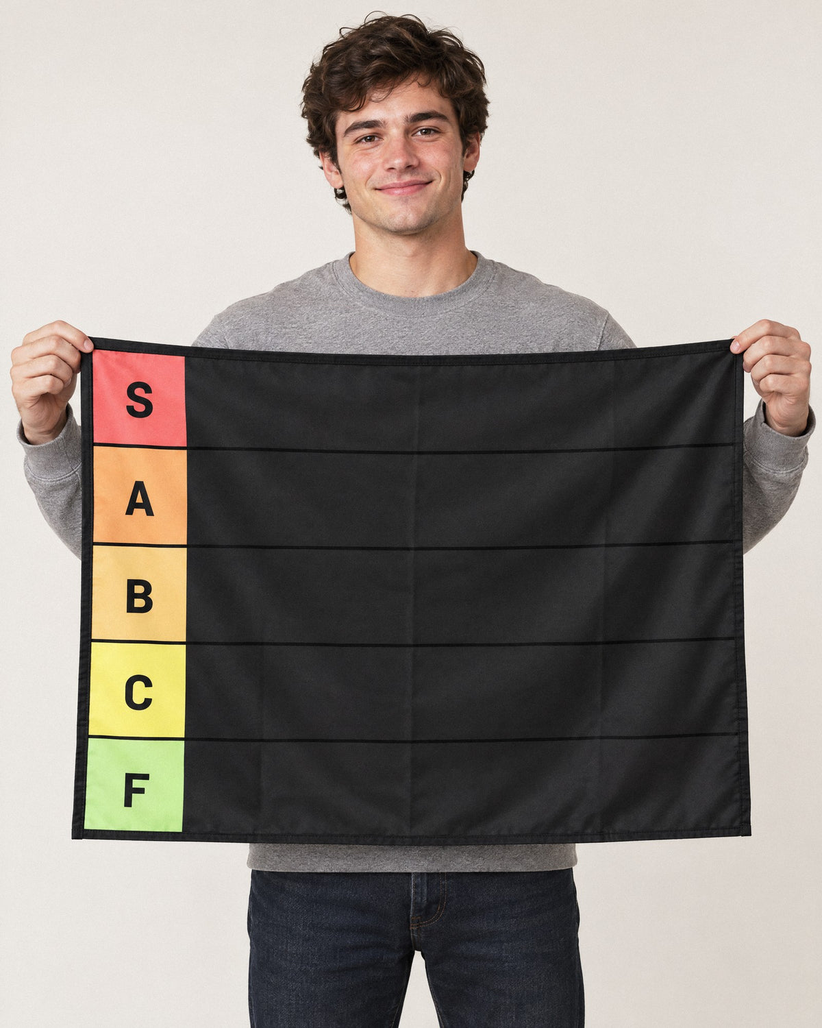 A guy holding up the 36 x 26 in tier list tapestry to show its size