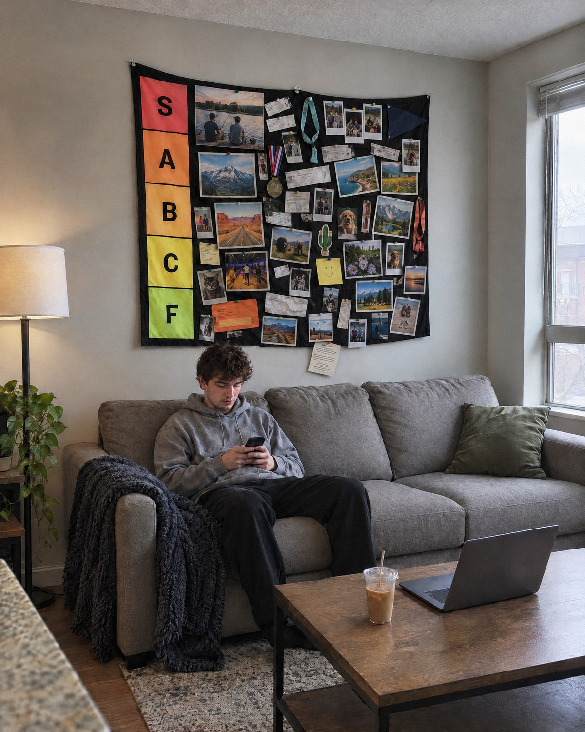 XL tier list wall tapestry filling the wall above a sofa, a guy sitting below it for scale