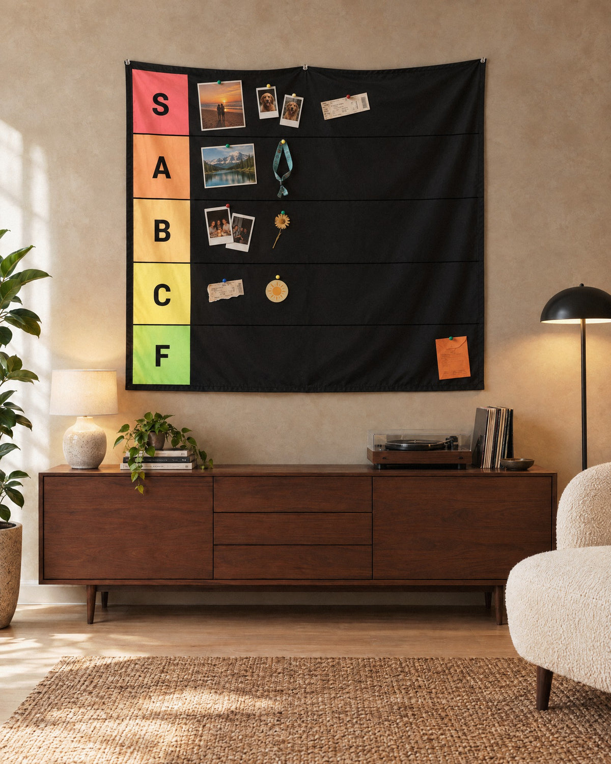 XL tier list tapestry above a walnut sideboard with a few photos and a wristband pinned